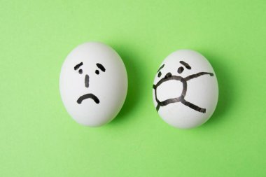 Yüzü olan yumurtalar: maskeli ve üzgün. Karantina konsepti covid 19.