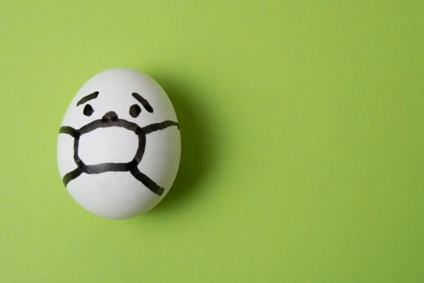 Huevo con una persona en una máscara, sobre un fondo verde. Concepto cuarentena covid 19 — Foto de Stock