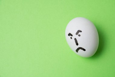 Kötü yüzlü bir yumurta, yeşil arka planda fotokopi alanı var.