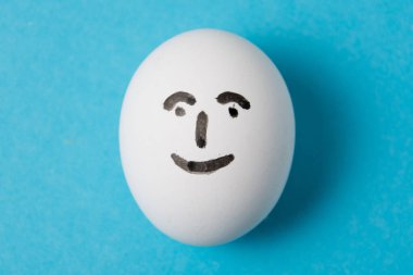 Mutlu, neşeli yüzlü bir yumurta. Mavi arkaplanda izole et