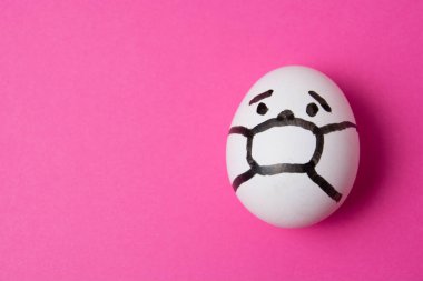 Yüzünde maske olan bir yumurta. Fotokopi alanı olan pembe bir arka plan. İlaç konsepti Covid 19 'u karantinaya al