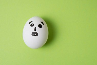 Şaşırmış yüzlü yumurta, yeşil bir arka planda mesaj için yer var