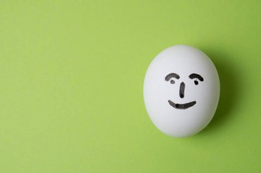 Neşeli ve neşeli bir yüzü olan yumurta, fotokopi alanı olan yeşil bir arka plan..