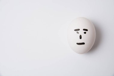 Yüzünde kayıtsız bir duygu olan bir yumurta, beyaz arkaplan fotokopi alanı