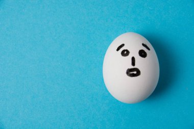 Şaşırmış bir suratı olan yumurta. Mavi arkaplanda izole et