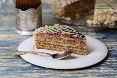 Açık mavi ahşap arka planda fındıklı, kremalı, çikolatalı ve çaylı iştah açıcı kek.