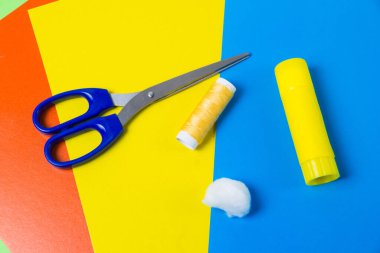 Makas, yapıştırıcı, pamuk ve iplikler çok renkli karton çarşaf üzerinde. Paskalya için el yapımı çelenkler yapma süreci