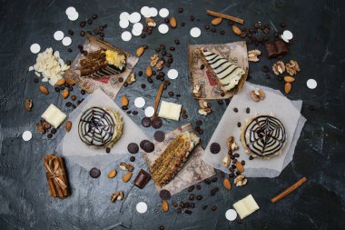 Bir sürü pasta ve pasta, çikolata, krema ve tarçın. Koyu bir arka planda. Boşluğu kopyala..