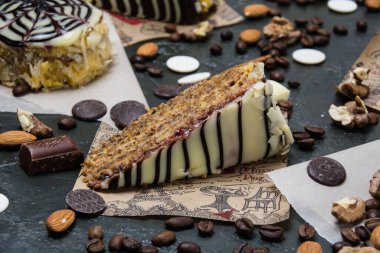 Kremalı, beyaz ve siyah çikolatalı pasta, krema, fındık, badem üzerine koyu arkaplan ve metin için bir yer..