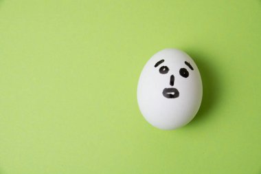 Şaşırmış yüzlü yumurta, yeşil bir arka planda mesaj için yer var.