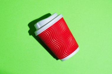 Kahve için kırmızı kağıt bardak ya da yeşil arka planda çay. Fotokopi alanı olan renkli bir arkaplanda tek kullanımlık tablo yazılımı