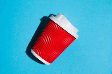 Kahve için kırmızı kağıt bardak ya da mavi arka planda çay. Fotokopi alanı olan renkli bir arkaplanda tek kullanımlık tablo yazılımı