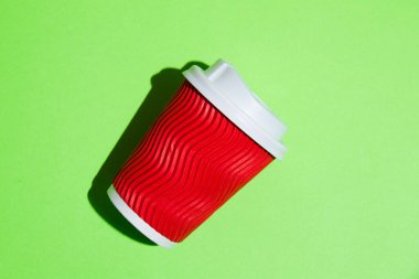 Kahve için kırmızı kağıt bardak ya da yeşil arka planda çay. Fotokopi alanı olan renkli bir arkaplanda tek kullanımlık tablo yazılımı