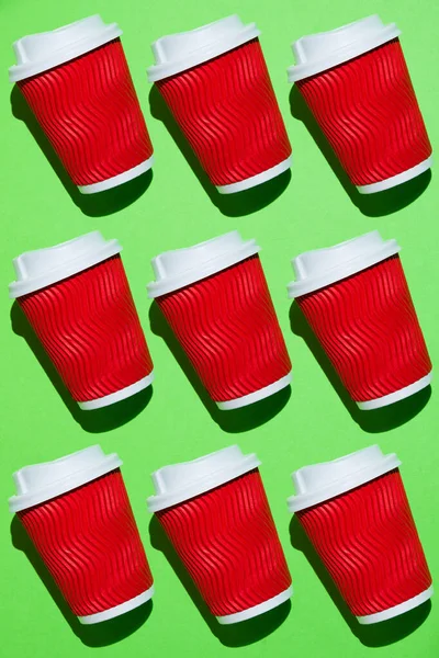 Pasttern, kahve için bir sürü kırmızı kağıt bardak ya da yeşil arka planda çay. Fotokopi alanı olan renkli bir arkaplanda tek kullanımlık tablo yazılımı