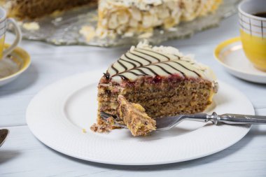 Beyaz tabakta çatal ve açık ahşap bir masada sarı kahve ile çok lezzetli bir kek dilimi. Pasta yeme ve tatlı yiyeceklerin tadını çıkarma süreci..
