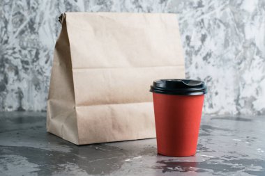 Kırmızı kağıt bardak ve gri arka plan fotokopi alanındaki paket paketi. Karantina sırasında restoran işletmesinin gelişimi ve gıda teslimatı konsepti..