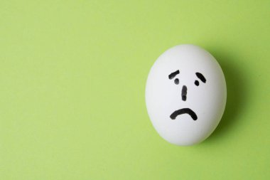 Üzgün yüzlü yumurta, yeşil arka planda kopya alanı ile