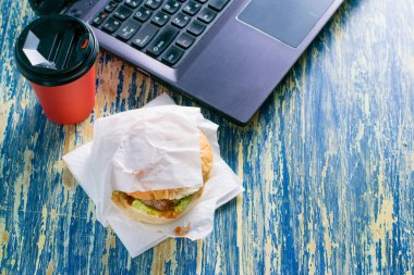 Sığır pirzolası, sos, salata, kağıt bardak ve dizüstü bilgisayar manzaralı paket kahve. Yemek teslimatı konsepti, ofiste öğle yemeği.
