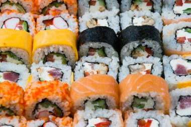 Avokado, somon, çedar peyniri, yengeç çubuğu, havyar, ton balığı, nori, salatalık ve krem peynirli büyük bir suşi rulosu..