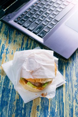 Biftek köfteli burger, sos ve salata yiyecek ve laptop manzaralı fotokopi alanı için el çantasına. Yemek teslimatı konsepti, karantina bölgesi 19 'daki restoranlar..