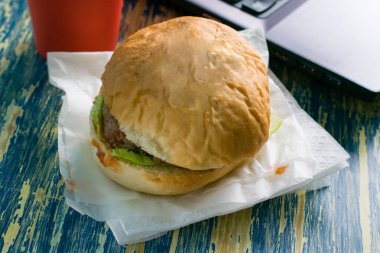 Sığır pirzolası, sos, salata, kağıt bardak ve dizüstü bilgisayar manzaralı paket kahve. Yemek teslimatı konsepti, ofiste öğle yemeği