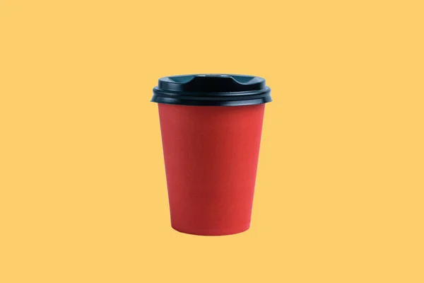 Red paper cup with plastic lid on light terracotta background.