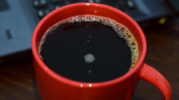 大きな赤いカップにインスタントコーヒー 背景にラップトップ — ストック動画