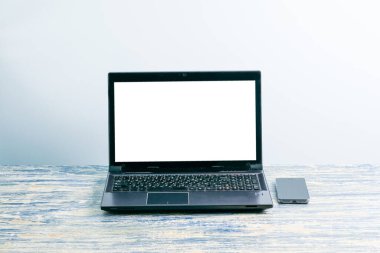 Laptop ekranı boş bir iş yeri, masadaki akıllı telefon.