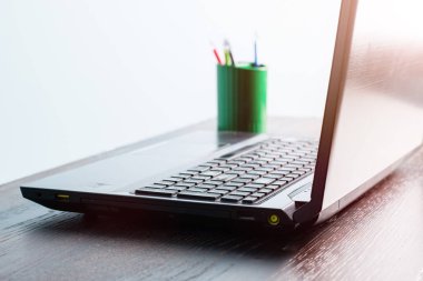 Laptop ve kalemler ahşap bir masada, yumuşak odaklı. Çevrimiçi öğrenme ve çalışma konsepti