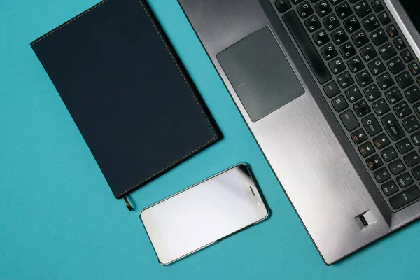 Flat lay, notepad, laptop and smartphone on a blue background, copy space, for a banner.