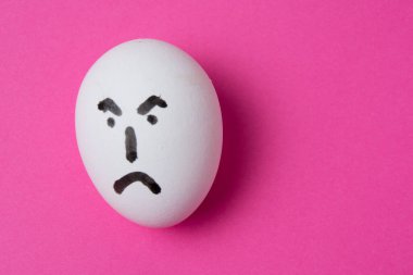 Fotokopi alanı olan pembe bir arka planda şeytani yüzlü bir yumurta.