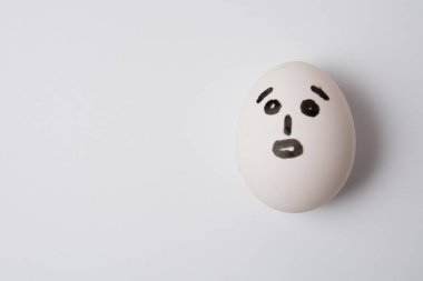 Beyaz arka planda, şaşırmış bir yüzü olan bir yumurta.