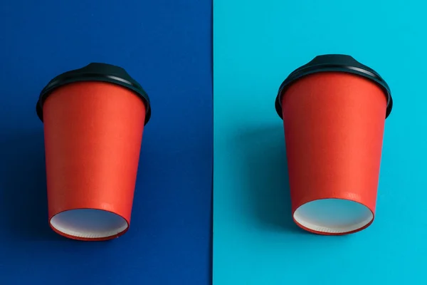 Red paper cups with plastic lids on bright paper backdrops copy space.
