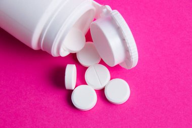 Pembe kağıtta beyaz haplar ve kavanoz arka plan fotokopi alanı üst görünümü.