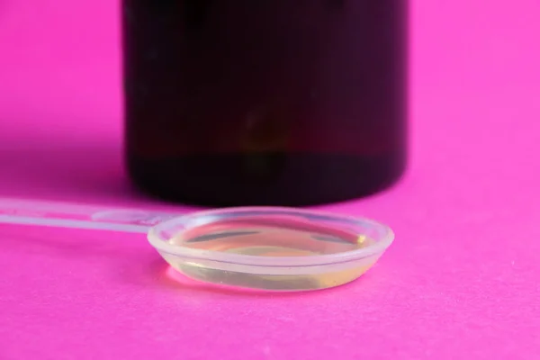 ピンクの背景のコピースペースの医学 透明なプラスチック製のスプーンで薬 — ストック写真