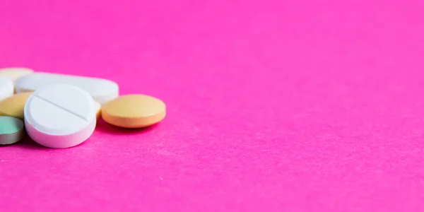 Pills on pink paper background with copy space. Covid 19 treatment concept, banner format.