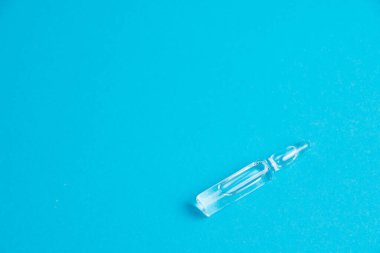 Mavi arka plan makrosu üzerinde ilaç bulunan ampul, kopyalama alanı. Coronavirüs hastaları için tedavi kavramı.