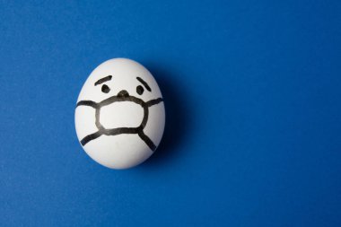 Yüzünde maske olan bir yumurta. Fotokopi alanı olan mavi bir arka plan. İlaç konsepti Covid 19 'u karantinaya al.