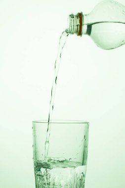 Bir adam şeffaf plastik şişeden bardağa su döker.