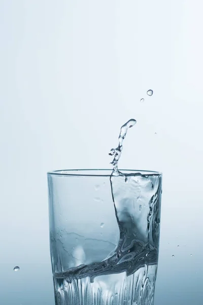 Water or alcoholic drink in a glass, splashing, splash closeup.