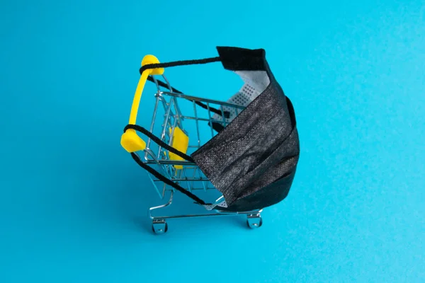 蓝色背景的购物者医疗面罩和超市购物车 Covid 19检疫限制概念 — 图库照片