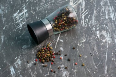 Koyu arkaplanda karabiber karışımı cam biber değirmeni, üst görünüm ve uzay kopyası.