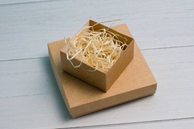 Craft gift boxes with light wood filling, on wooden background with copy space, top view.