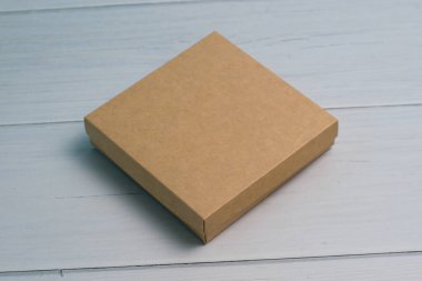 Closed craft gift box on a light wooden table. The concept of a gift for the holiday, what to give