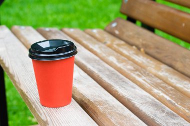 Bulutlu bir günde, bir yaz parkında, ahşap bir bankta kahve bardağı, kopyalama alanı. Park eğlencesi konsepti.