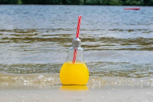 Świeża, lemoniada lub koktajl w szklanej butelce ze słomkowym zbliżeniem na piasku plażowym w pobliżu wody. Koncepcja podróży i rekreacji. — Zdjęcie stockowe