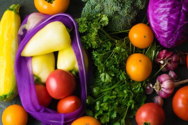 Bir sürü sebze: sarımsak, lahana, brokoli, kişniş, maydanoz ve domates. Tekrar kullanılabilir meyve ve sebze poşetinde sebzeler. Ekoloji koruma kavramı.