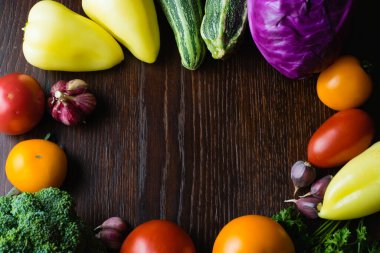 Vejetaryenlik ve düzgün beslenme kavramı. Sebze, domates, sarımsak, kabak, lahana, kişniş, ahşap masa üstünde biber, üst manzara, merkezde kopyalama alanı.