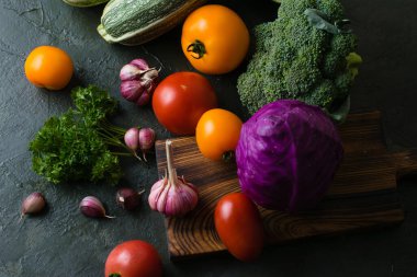 Sağlıklı beslenme konsepti. Koyu bir masanın üstünde bir sürü sebze, tepeden manzara..