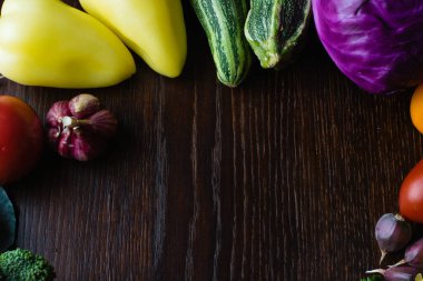 Vejetaryenlik ve düzgün beslenme kavramı. Sebze, domates, sarımsak, kabak, lahana, kişniş, ahşap masa üstünde biber, üst manzara, merkezde kopyalama alanı.